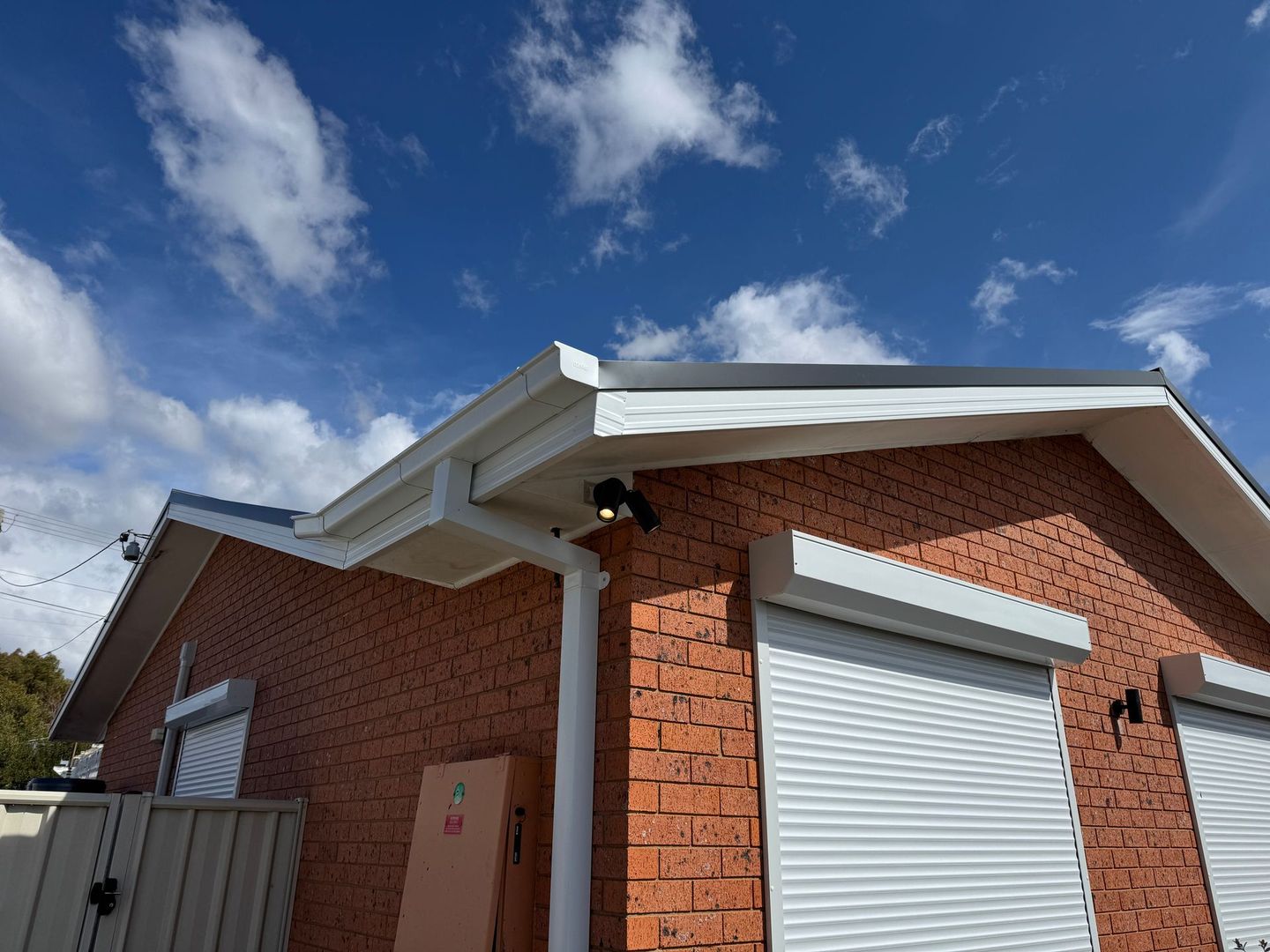white gutters on a house roof, with a blue sky backdrop — All Top Roofing In Royalla, NSW