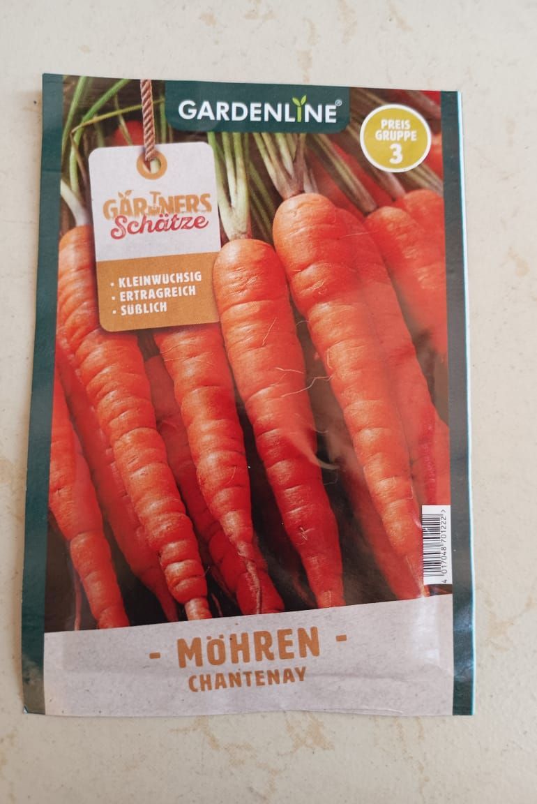 Gardenline carrot seed packet with orange carrots and German text on a beige background