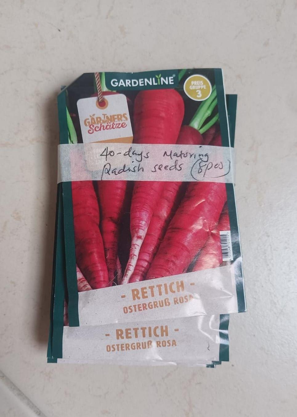 Seed packet for red radish “Gardenline,” showing pinkish-red roots and green tops.
