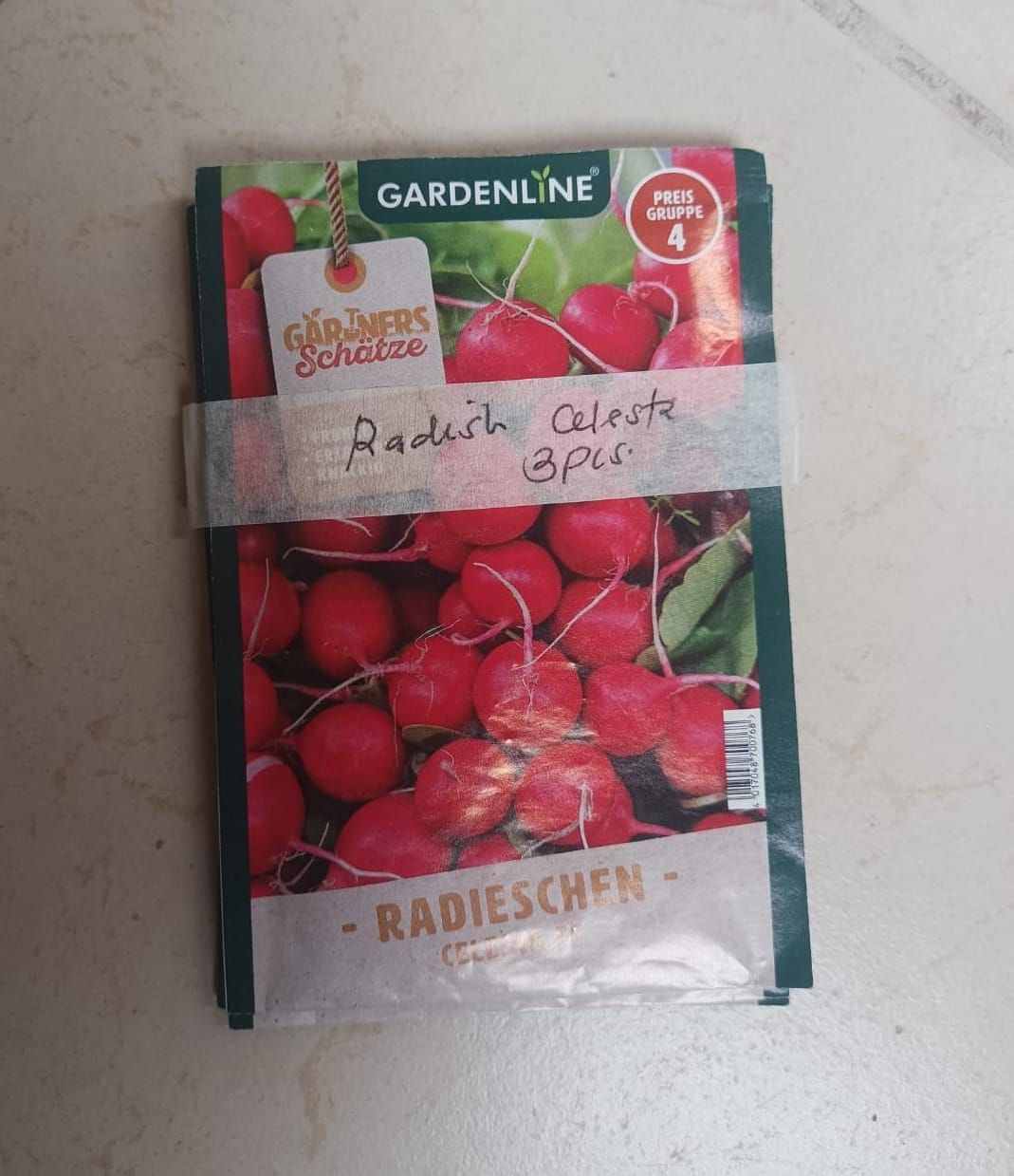 Radish seed packet with red radishes and handwritten label taped across the front.