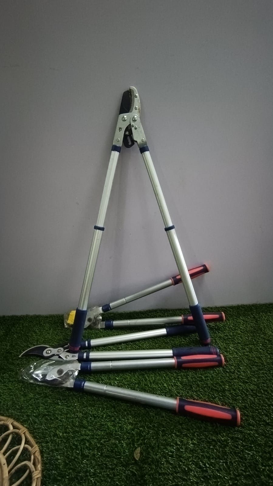 A metal tripod-like frame with red and white poles on green carpet against a gray wall.