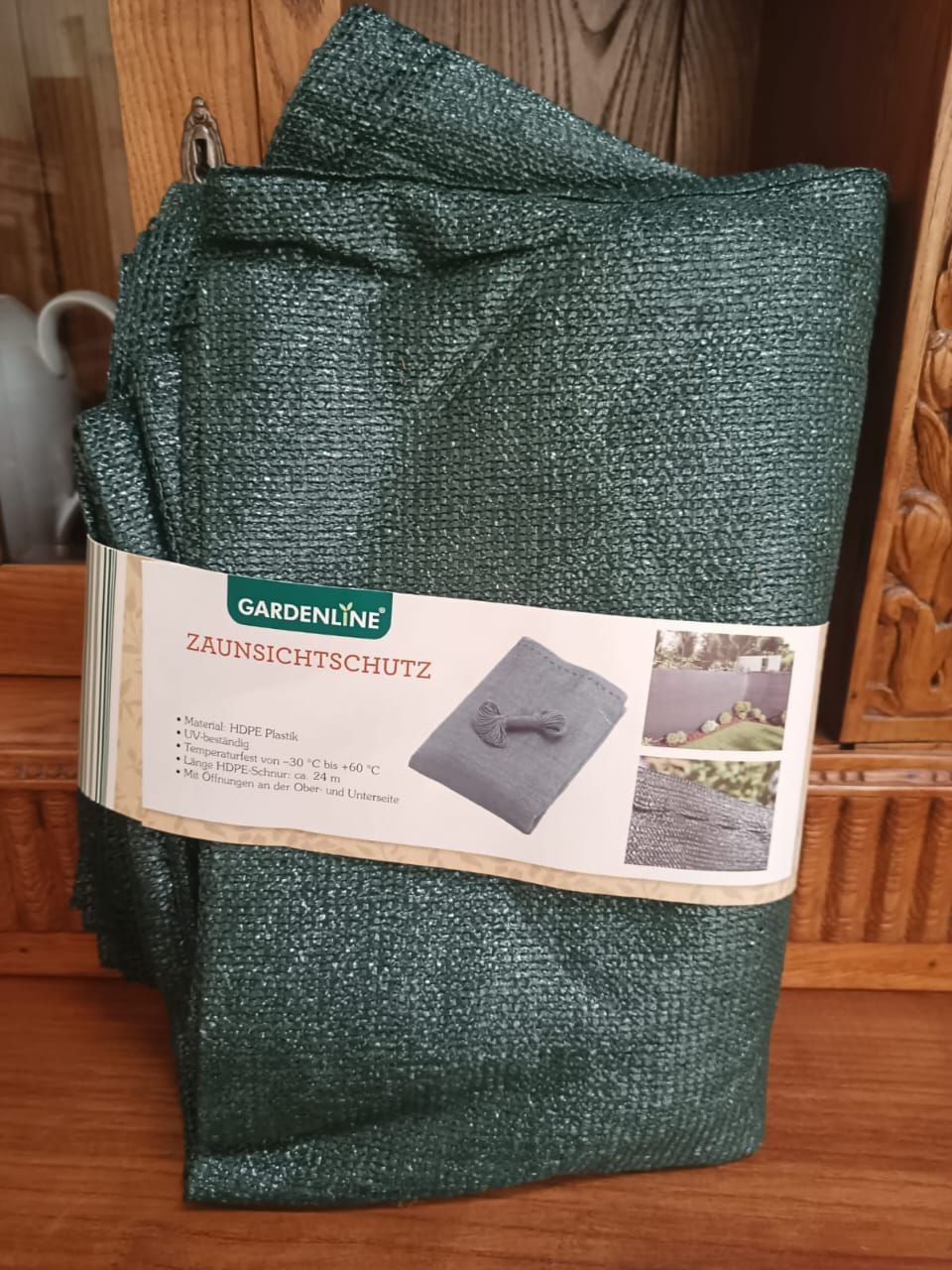 Green woven garden tarp package with product label and folded fabric standing upright