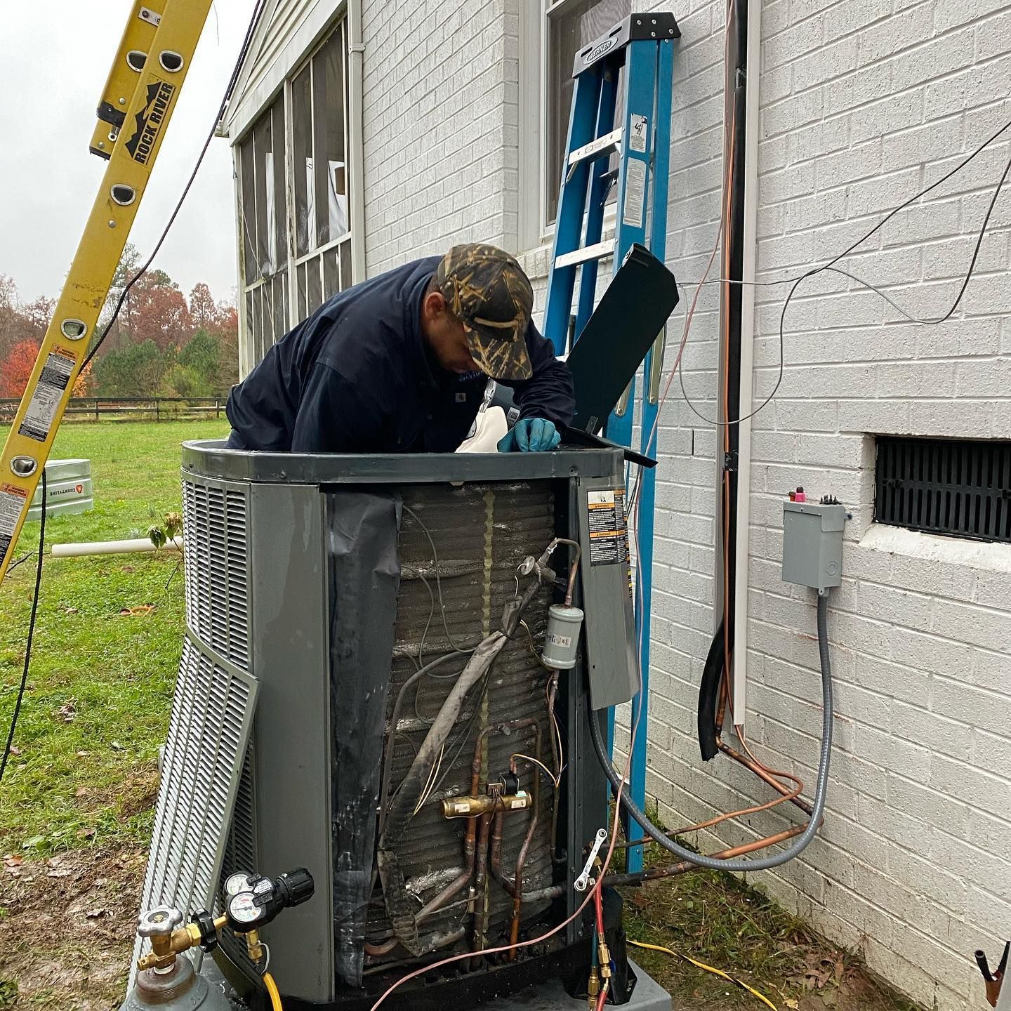 A man is working on an air conditioner outside of a building.