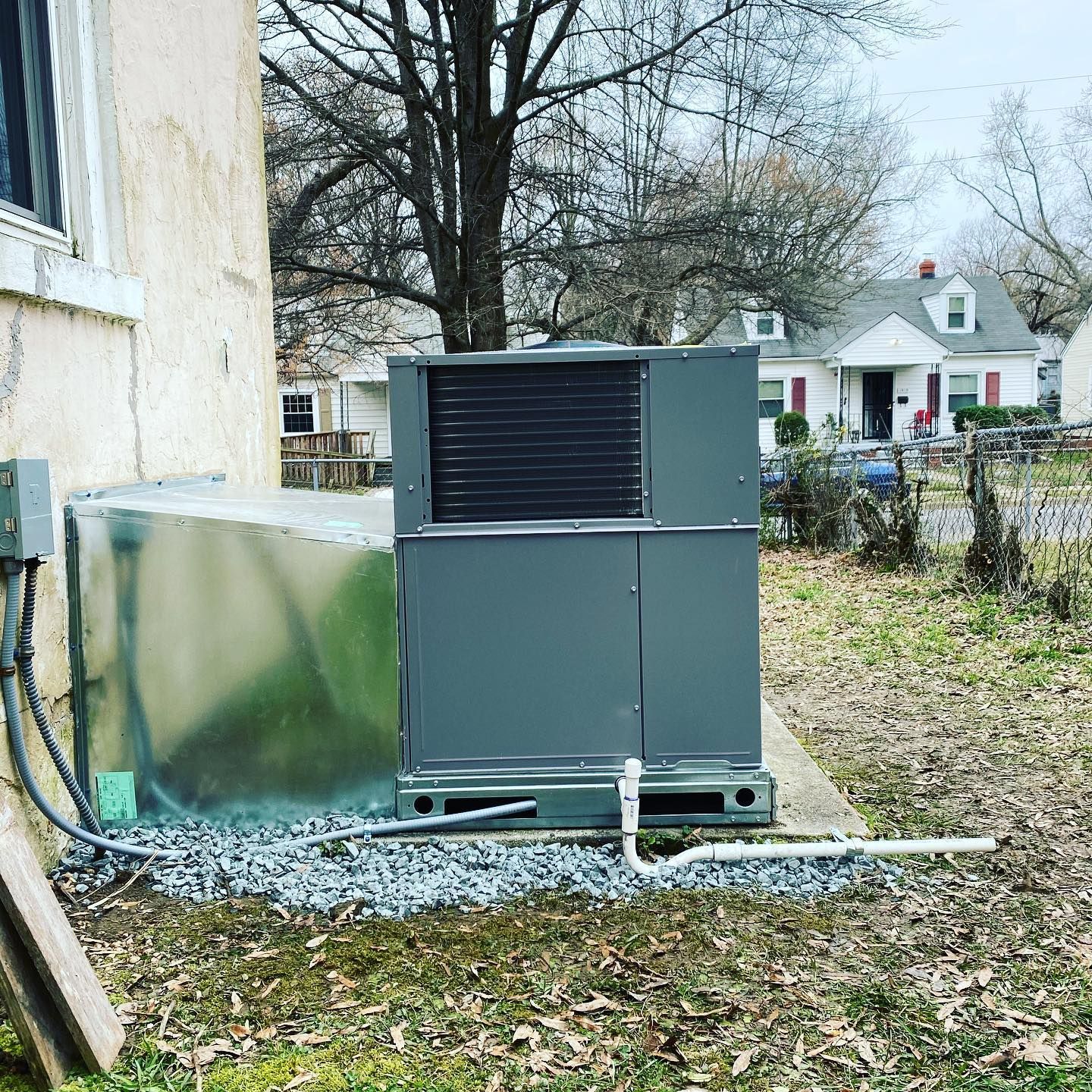 A large air conditioner is sitting on top of a concrete platform in front of a brick building.