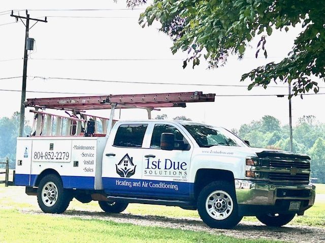 Blue and white HVAC service truck parked on grass, with ladder on top. Logo reads 