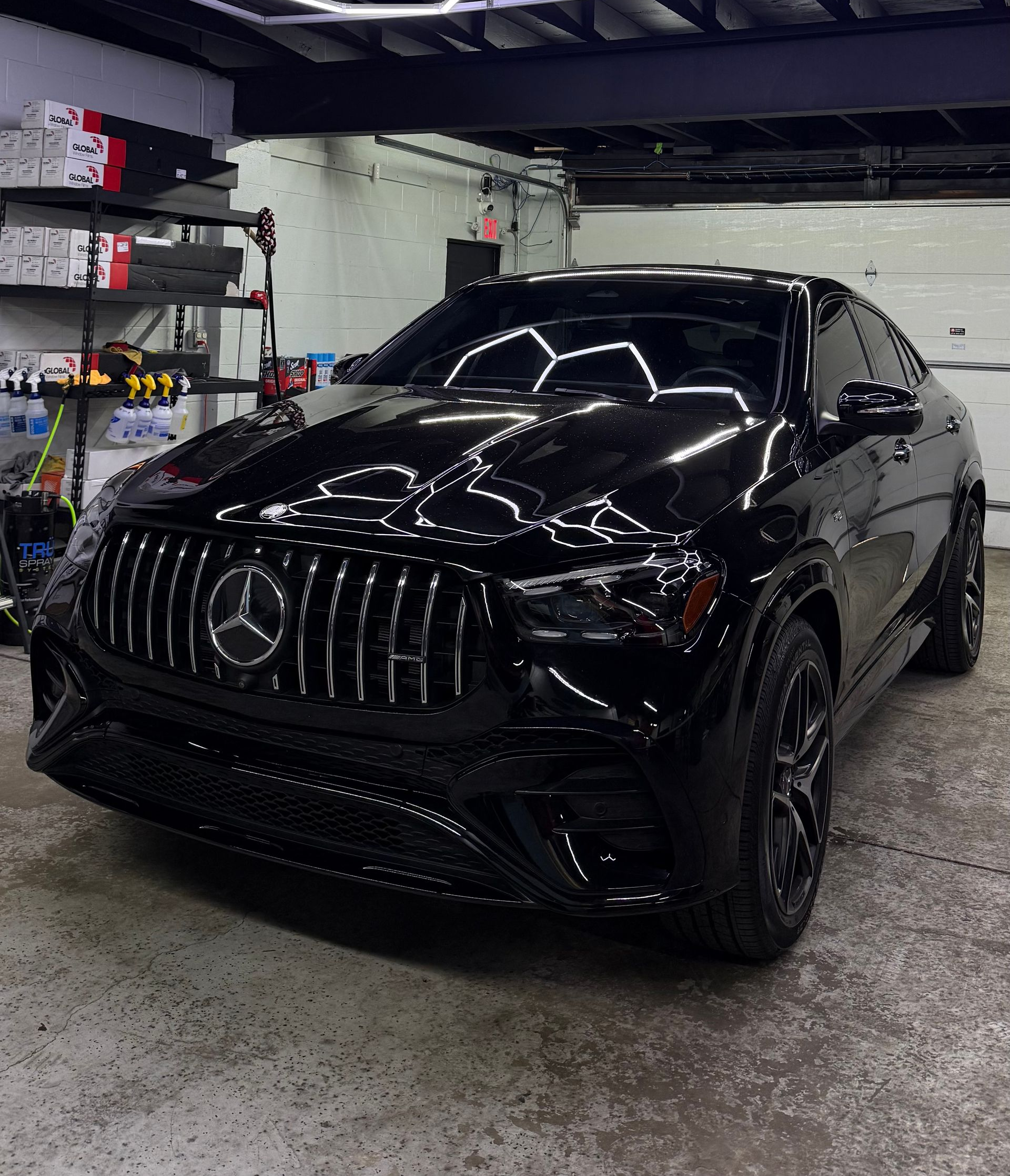 Black Mercedes sedan parked in an indoor garage, front view with glossy finish and dark rims