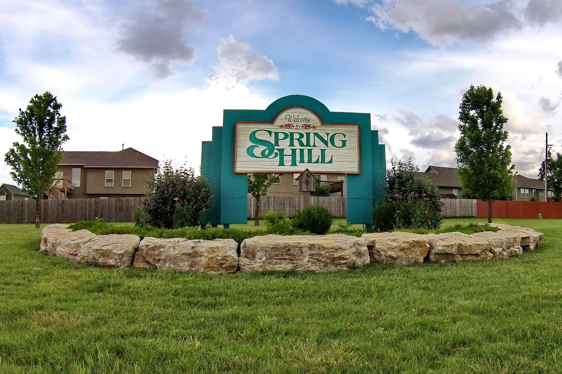 A sign for spring hill sits in the middle of a lush green field