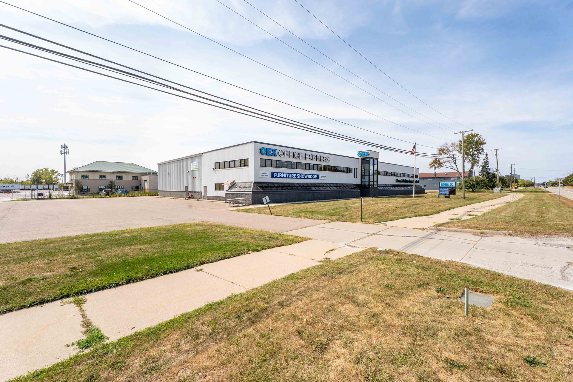 Building with a blue sign on a corner lot. Green grass, power lines, and blue sky.