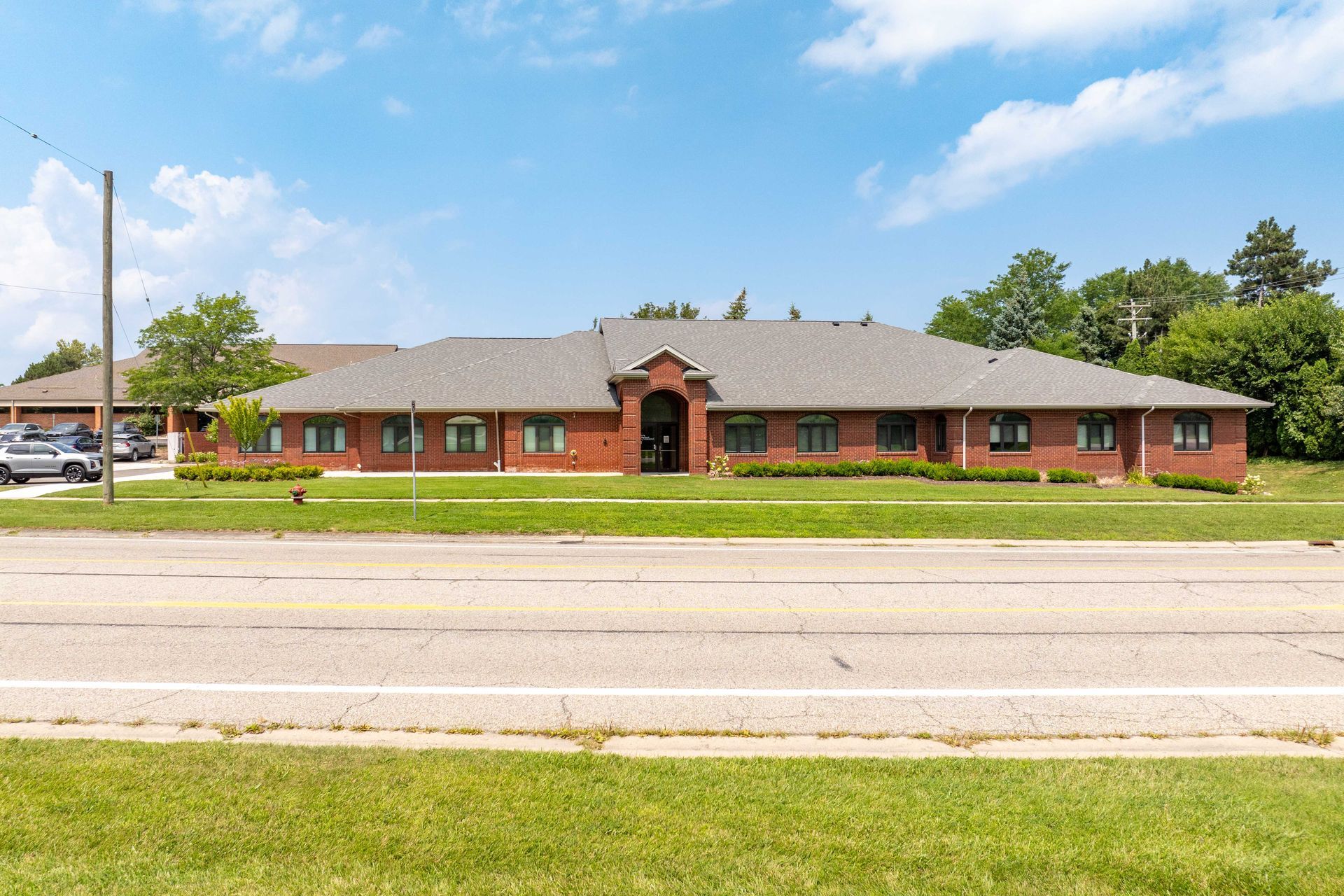 Red brick building with a dark roof and manicured lawn.