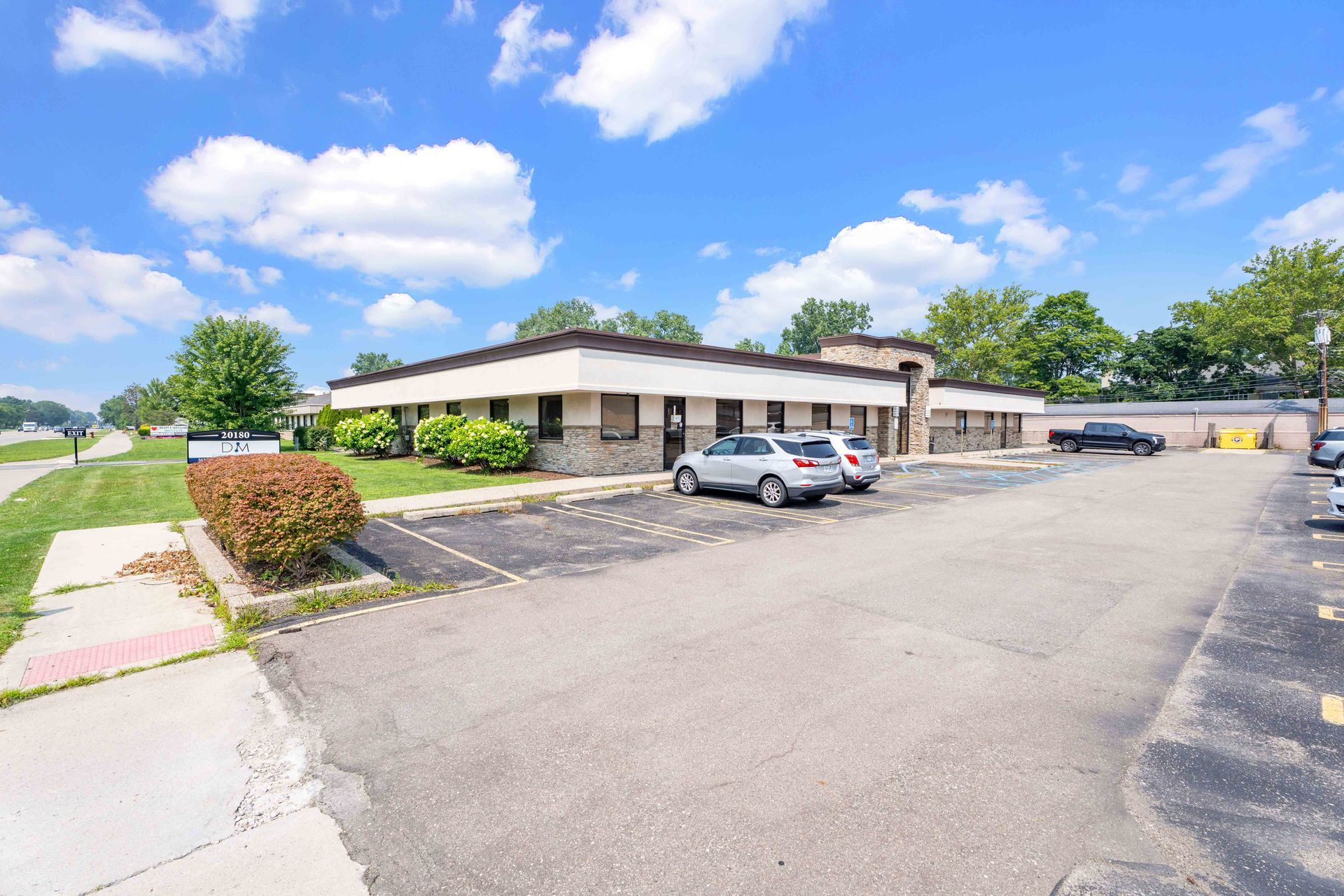 Commercial building with parking in front under a partly cloudy blue sky.