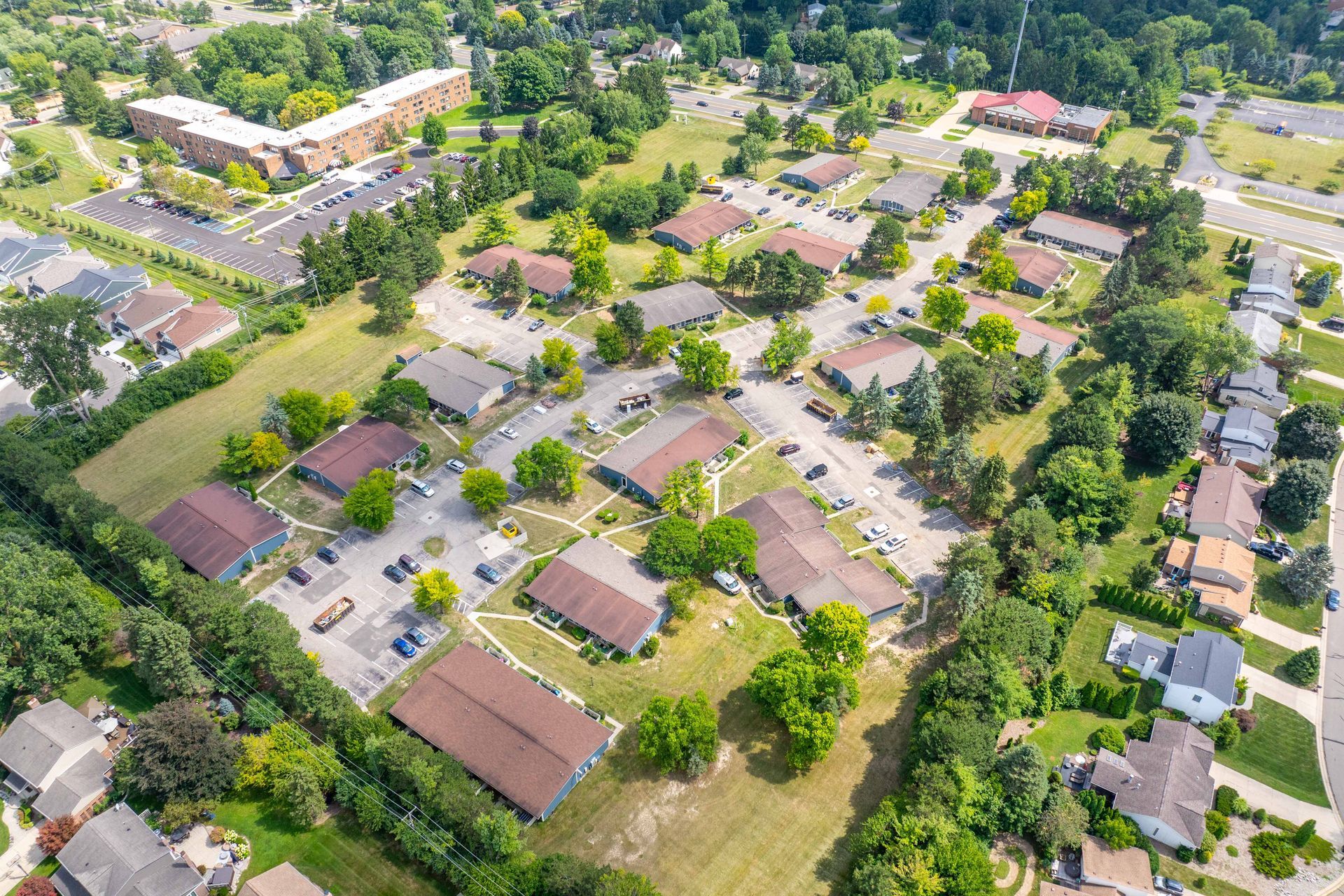 Aerial view of a suburban neighborhood with single-story buildings, parking lots, and trees.
