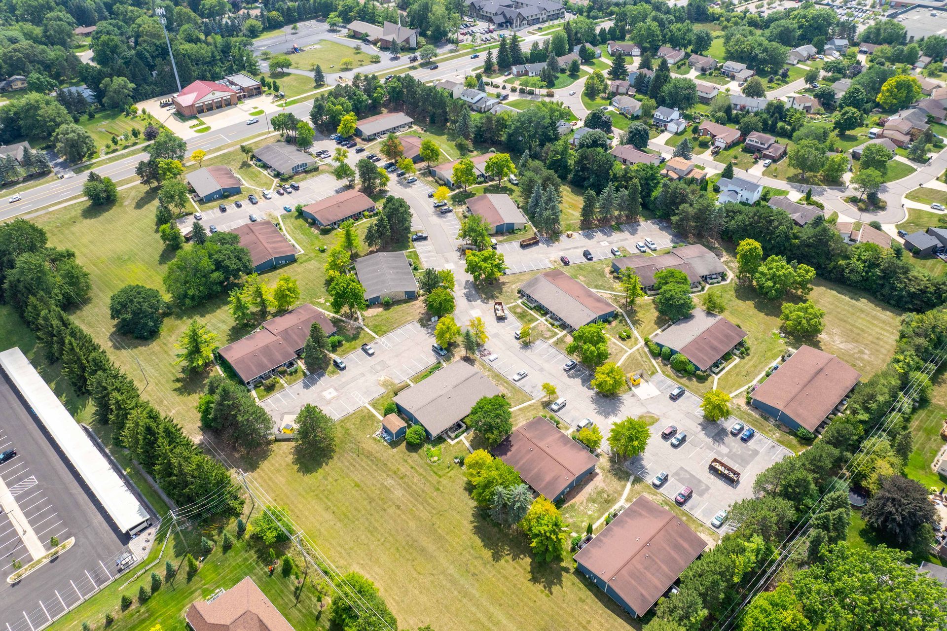 Aerial view of a suburban neighborhood with multiple one-story buildings, greenery, and parking lots.