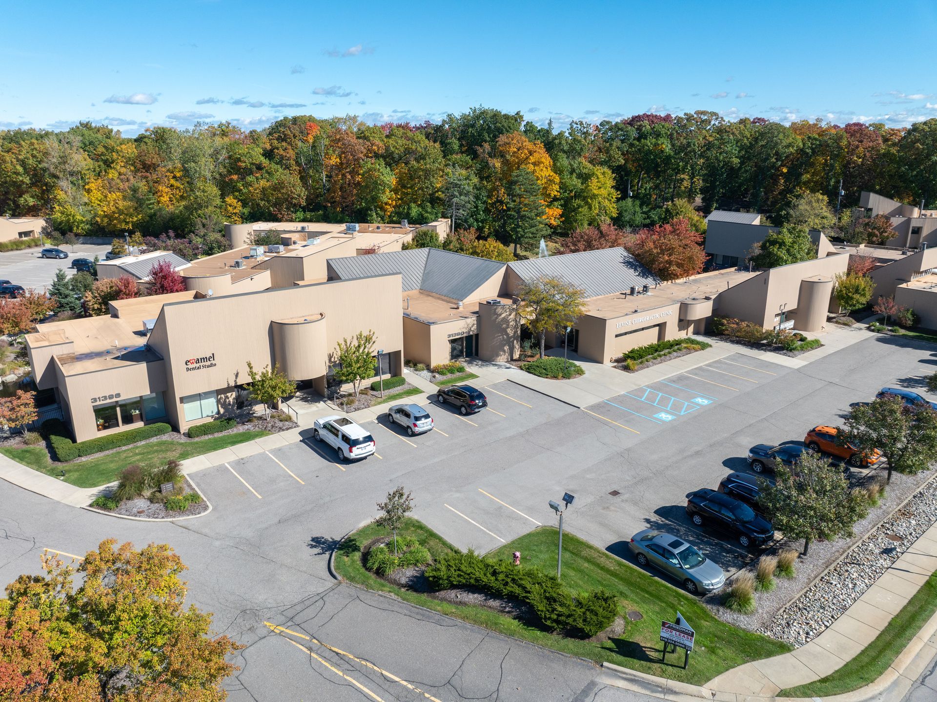 Office building with parking lot surrounded by trees in autumn.