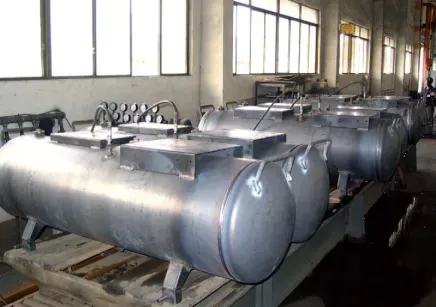A row of stainless steel tanks are sitting on a wooden table in a factory.