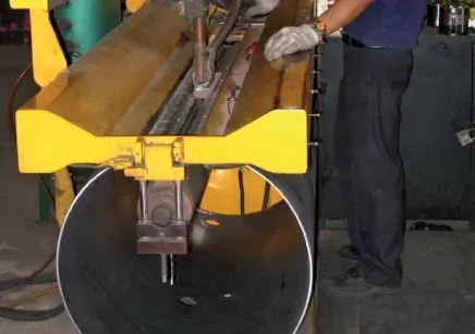 A man is working on a large metal pipe with a machine.
