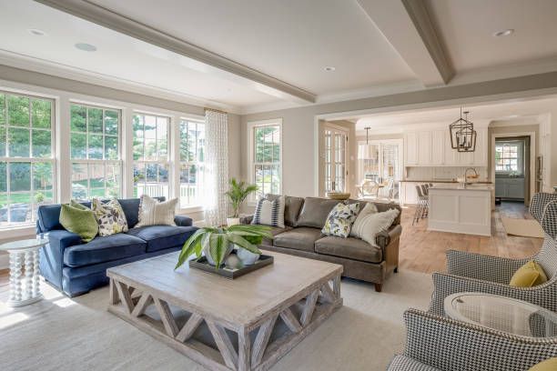 Bright living room with blue and gray sofas, a white coffee table, and large windows