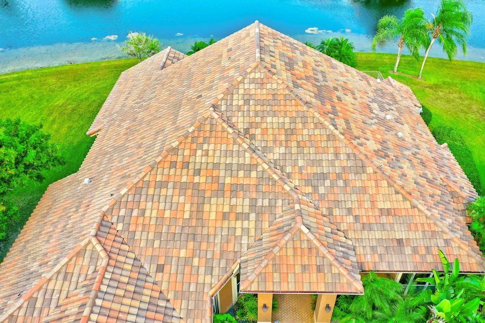 Tiled roof cottage beside bright turquoise water, surrounded by green palm trees and grass