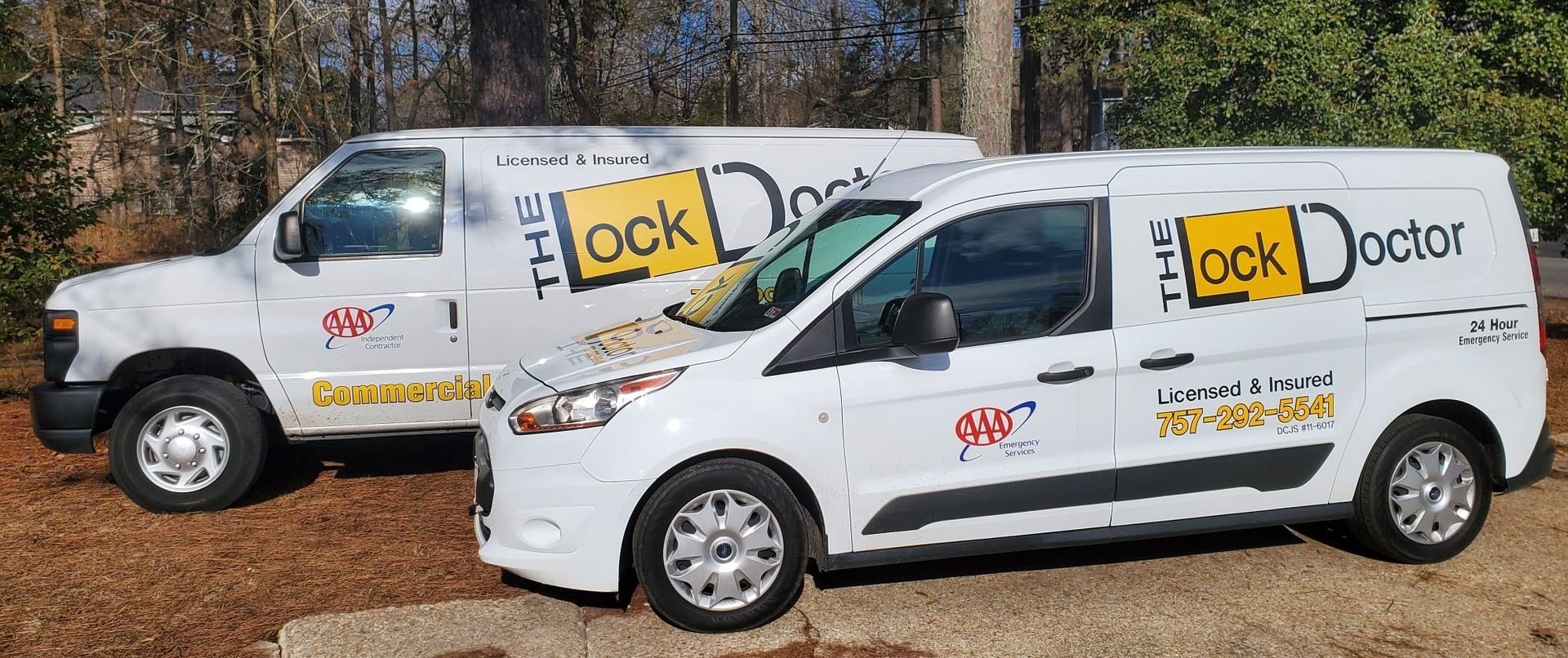 Two white vans are parked next to each other on a dirt road.