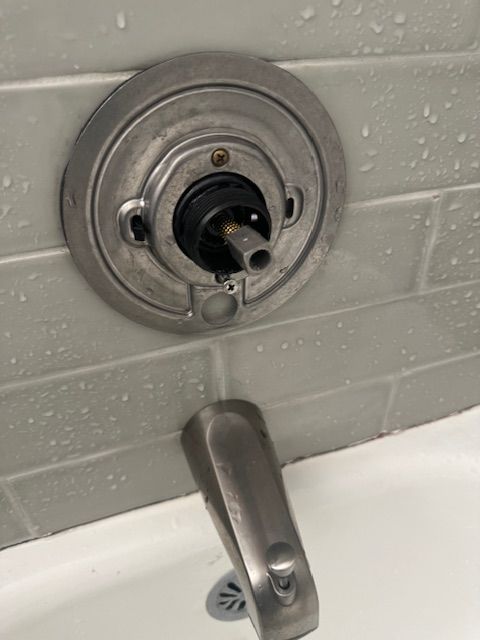 A close up of a faucet on a wall next to a bathtub