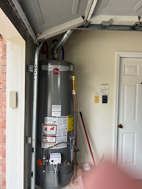 A water heater is sitting in a garage next to a door
