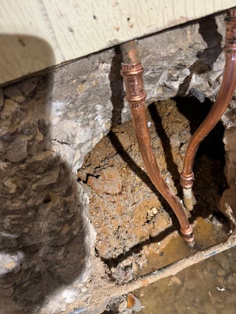 A close up of copper pipes in a hole in a wall