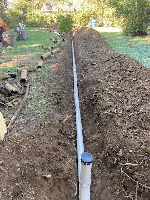 A pipe is being installed in the dirt in a yard