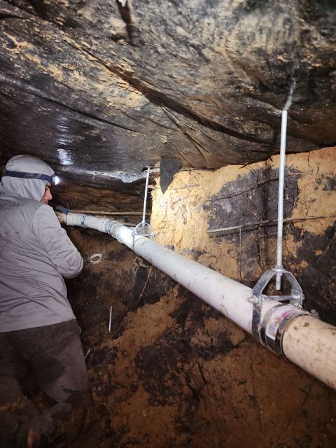A man is working on a pipe in a basement