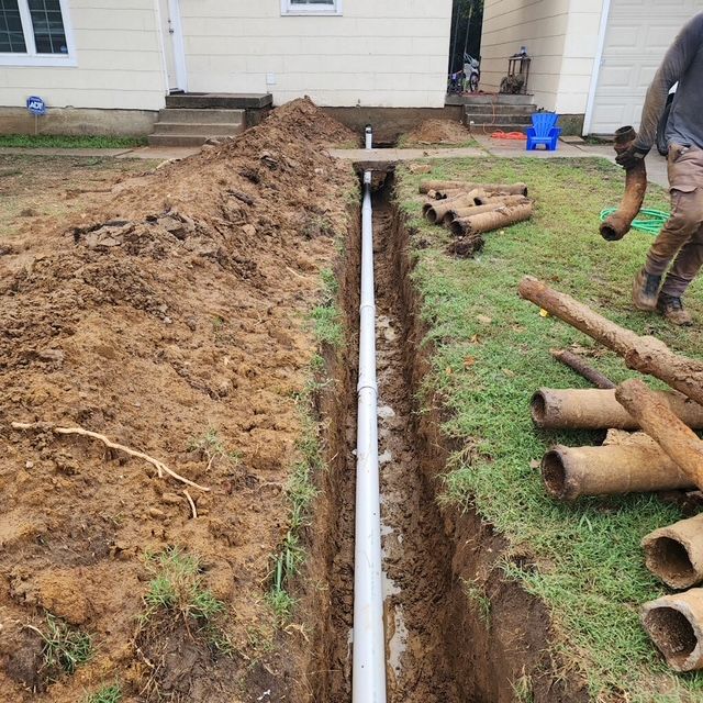 A man is digging a trench in front of a house