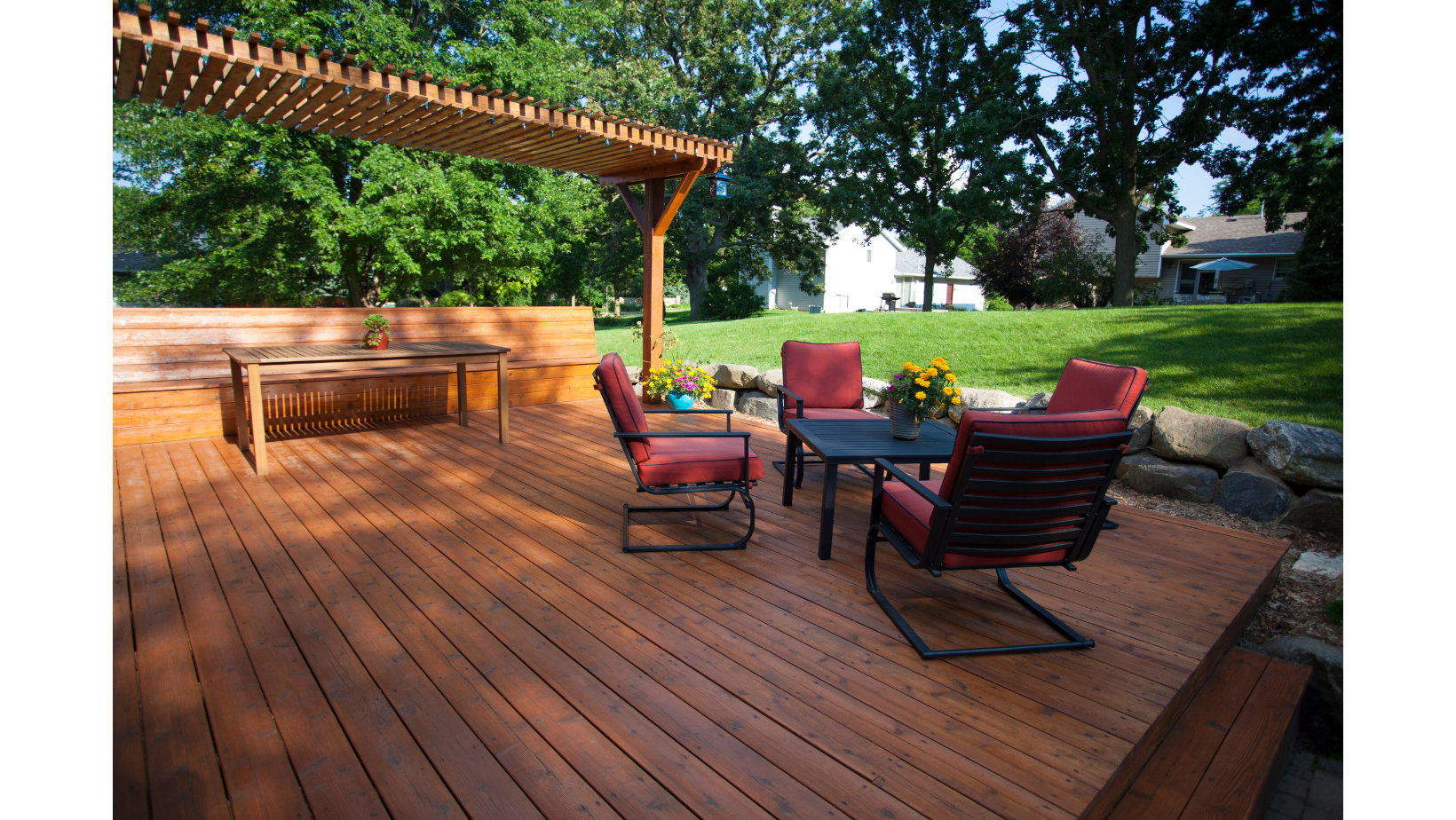 A wooden deck with chairs and a table under a pergola
