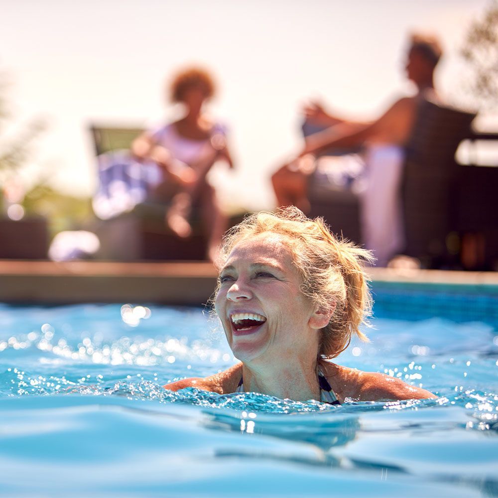 Smiling swimmer in a pool with people blurred in the background