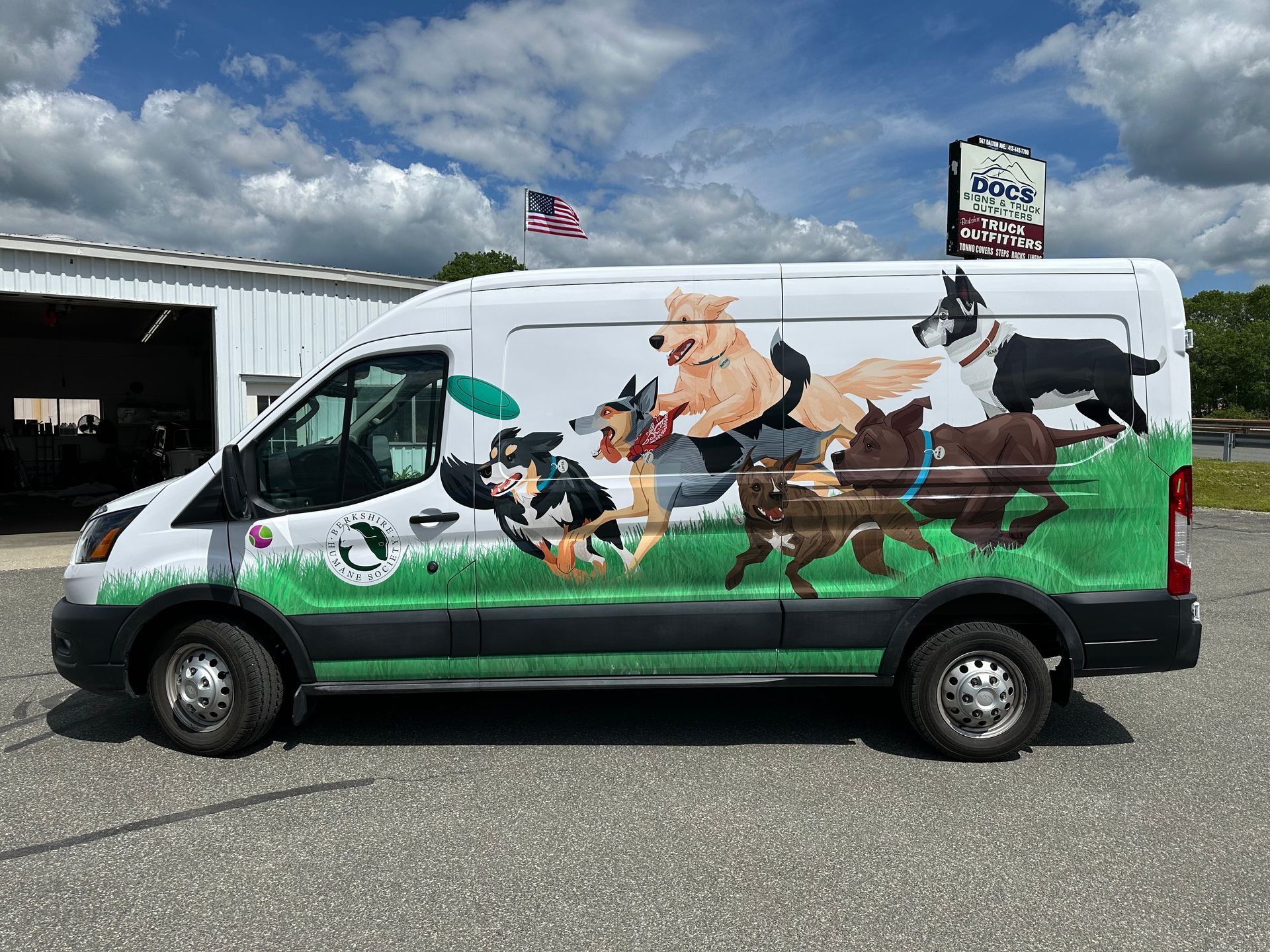 A van with a painting of dogs on the side is parked in a parking lot.