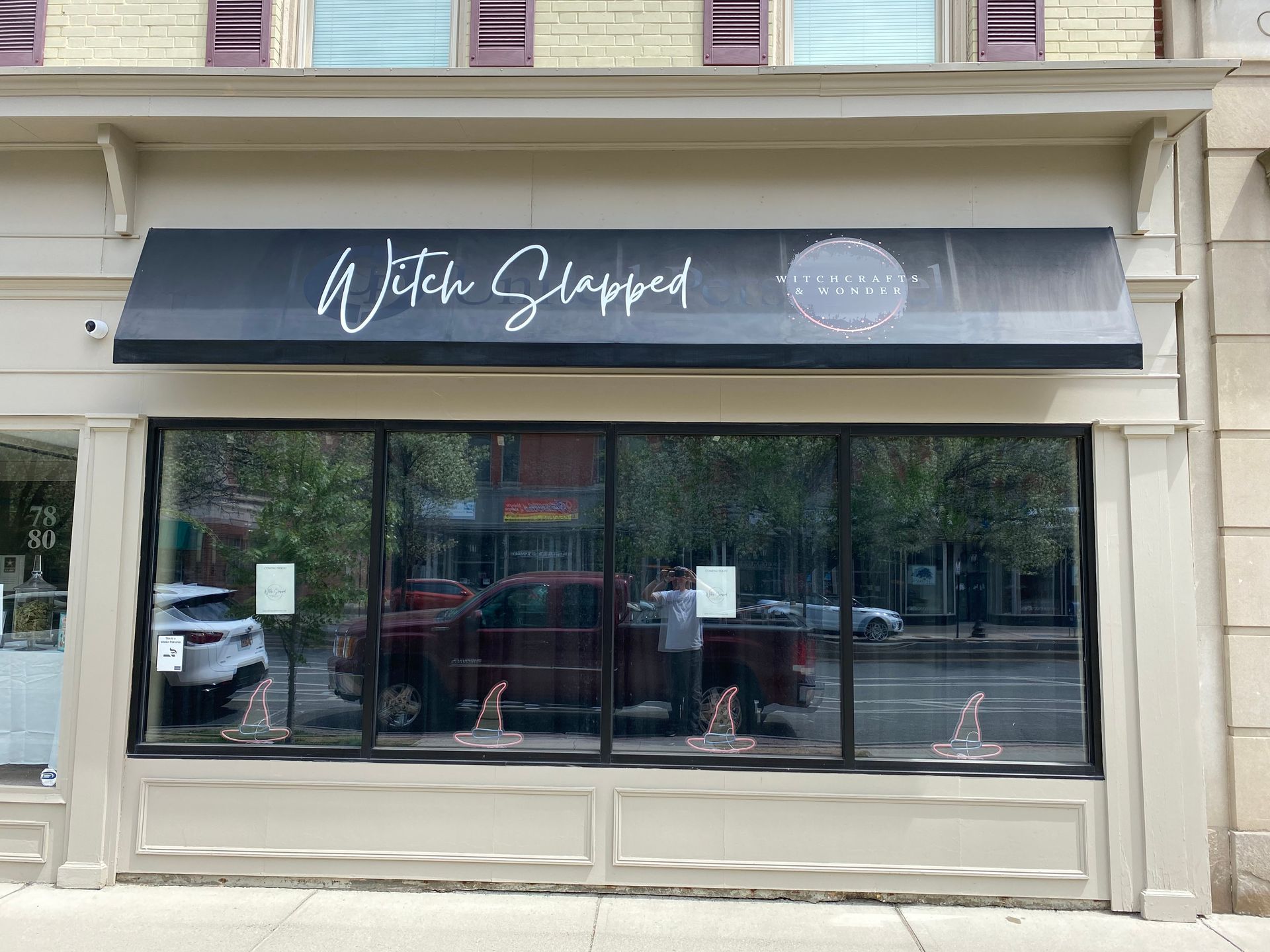 A store front with a black awning and a red truck parked in front of it.