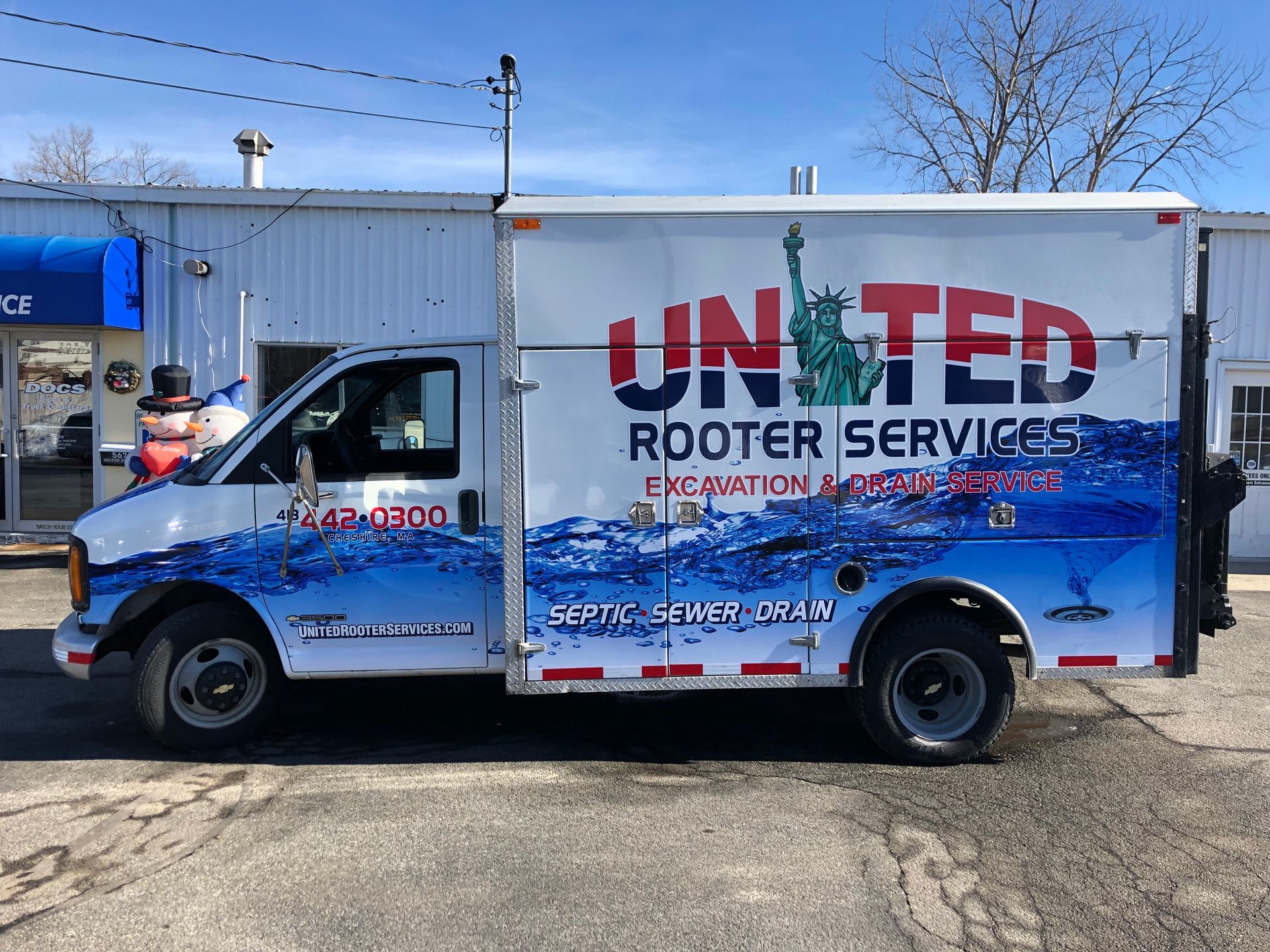 A united rooter services truck is parked in front of a building
