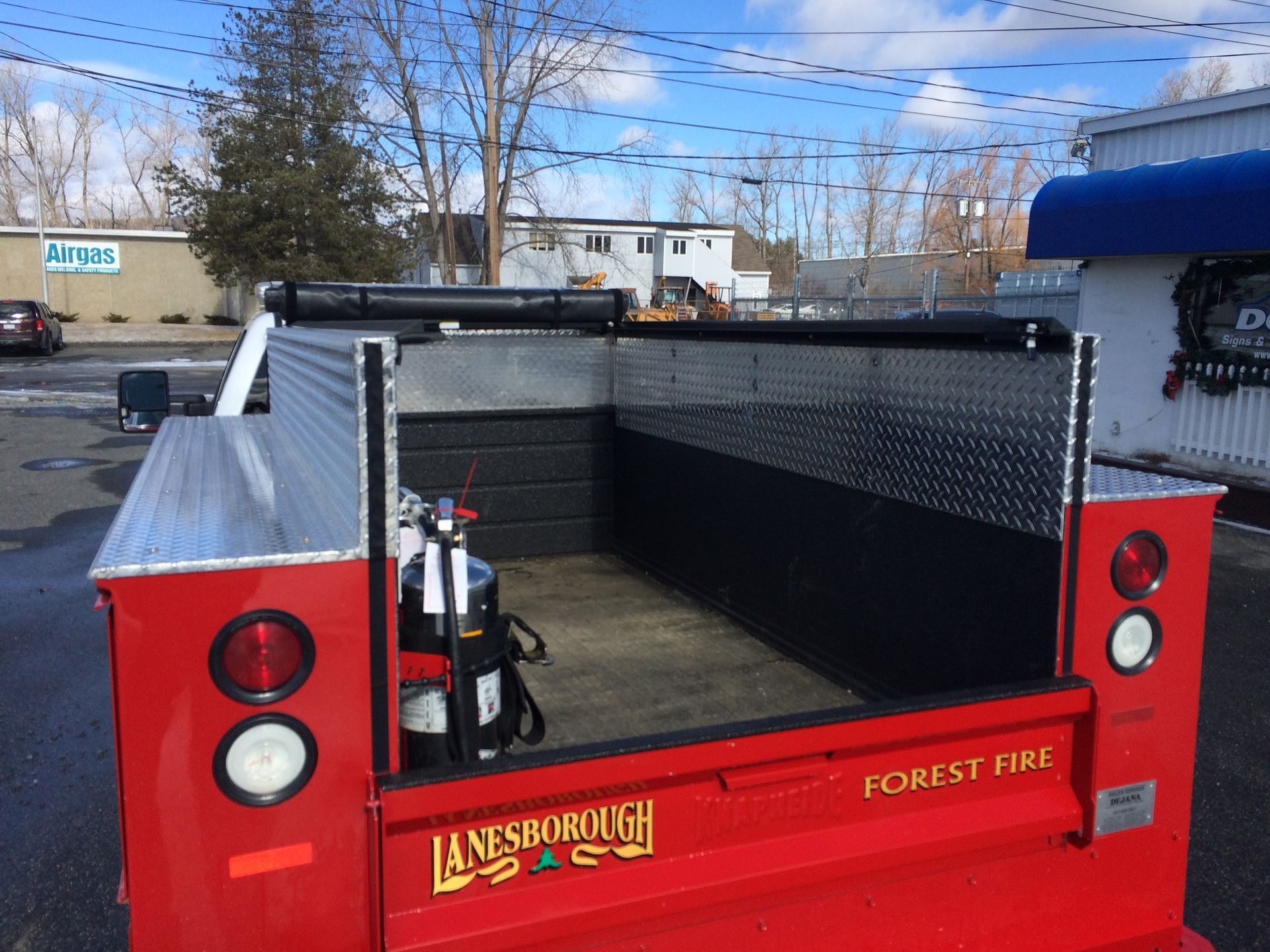 A red forest fire truck is parked in a parking lot