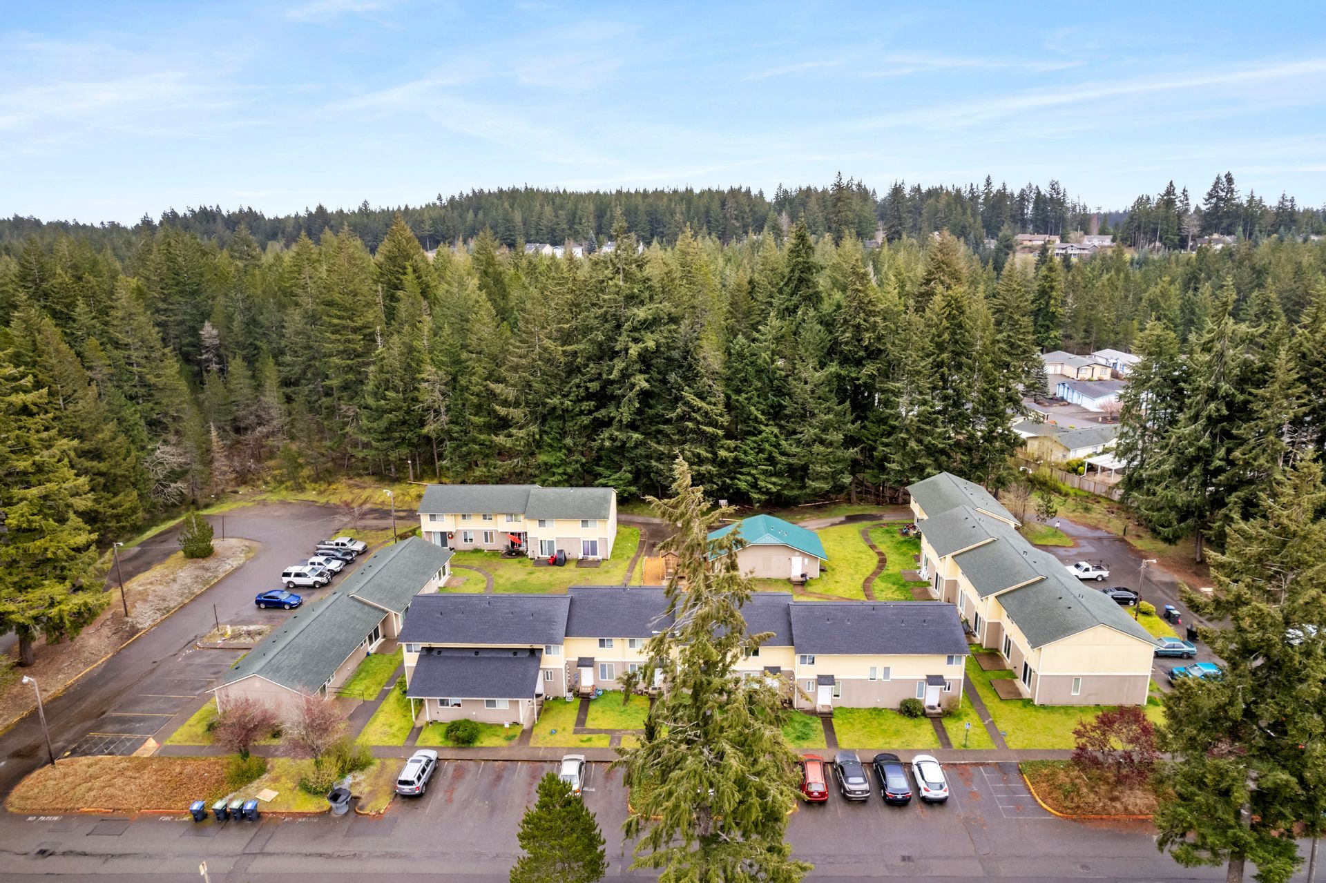 An aerial view of a residential area surrounded by trees and a parking lot.