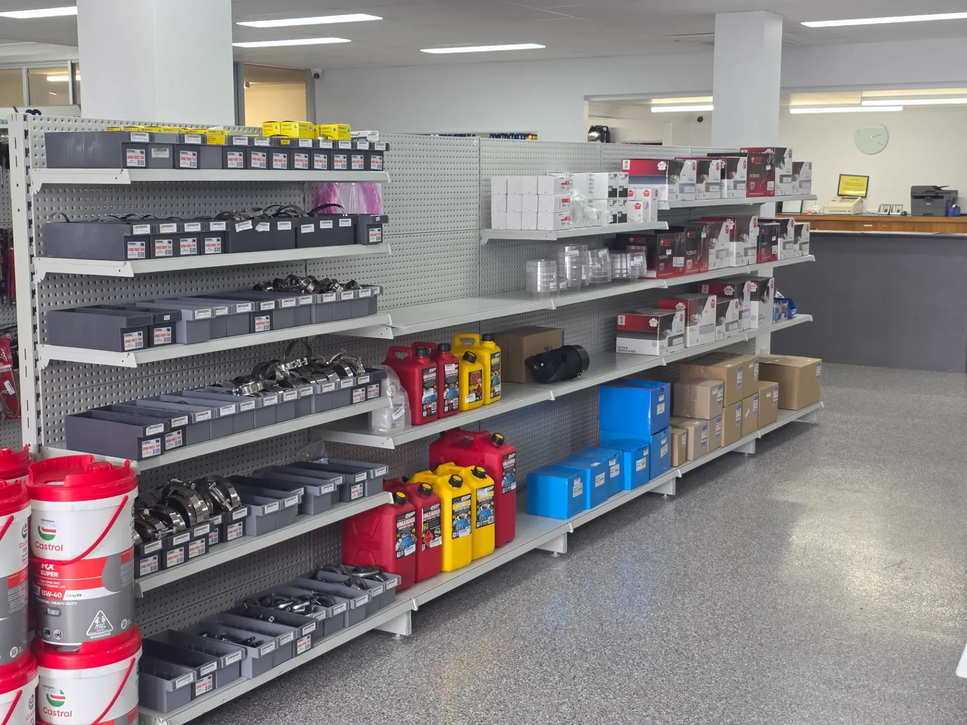 Store shelves filled with various automotive parts, oil containers, and boxed supplies in a bright, organized retail space.