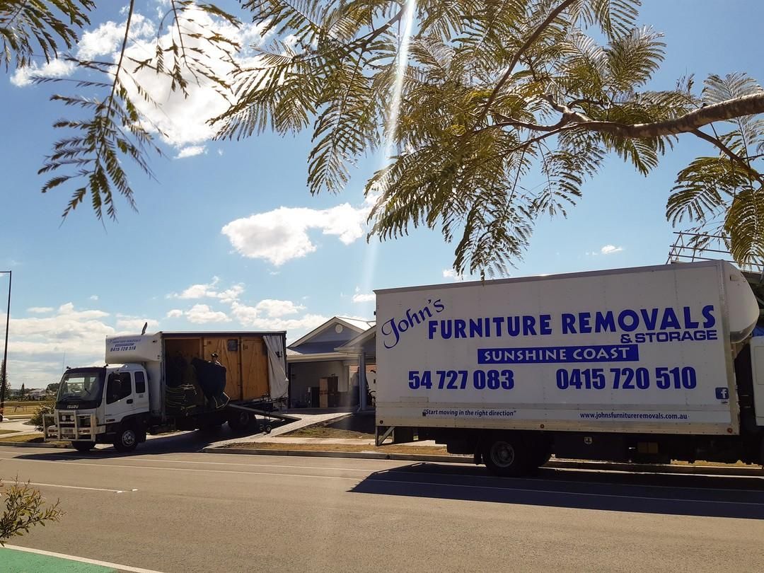 Moving Trucks Parked in Front of a House — John's Furniture Removals in Gold Coast, QLD