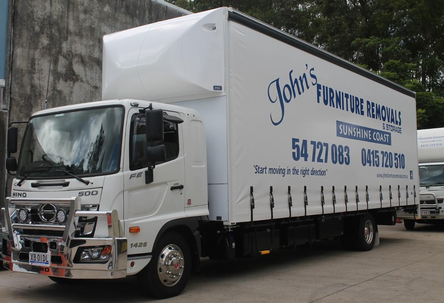 White Moving Truck With Company Logo and Contact Info Parked Outdoors — John's Furniture Removals in Caloundra, QLD