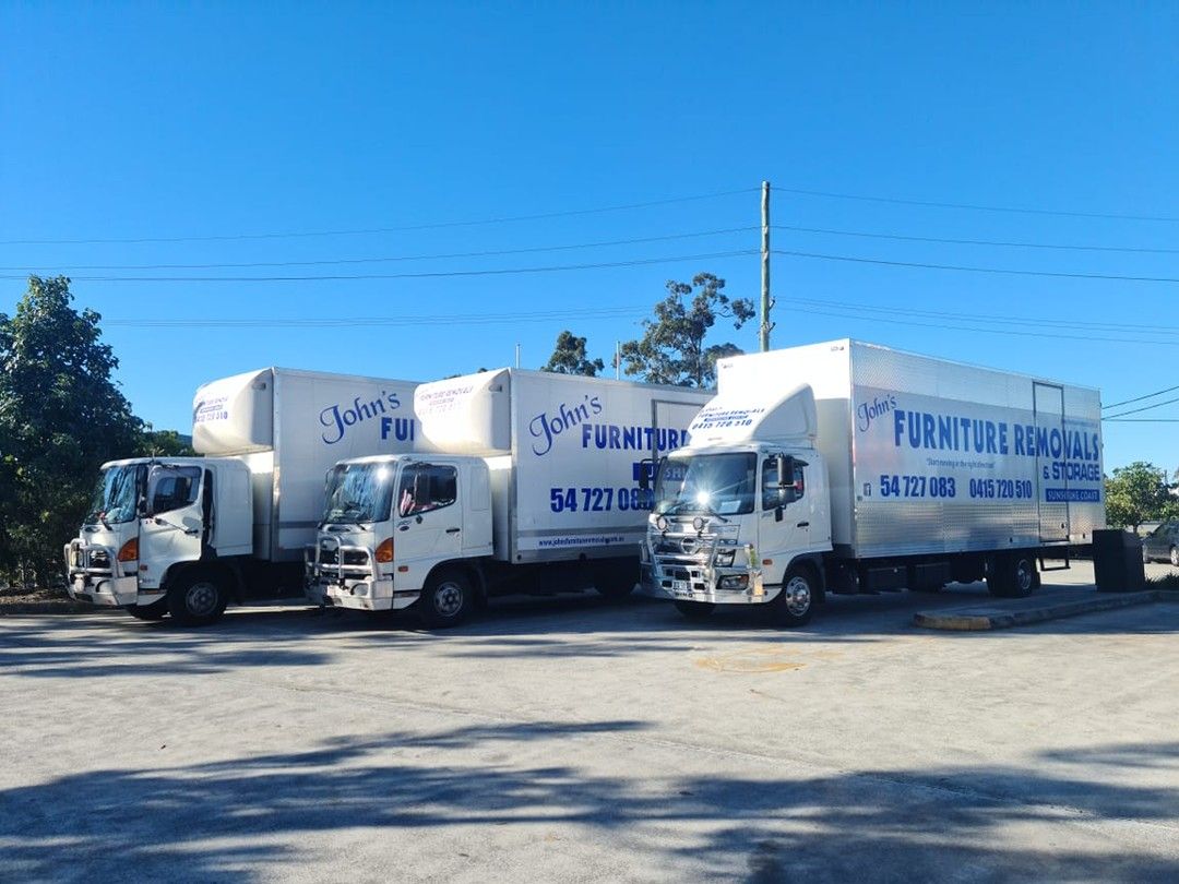 Three White Moving Trucks Parked on Asphalt on a Sunny Day — John's Furniture Removals in Sunshine Coast, QLD
