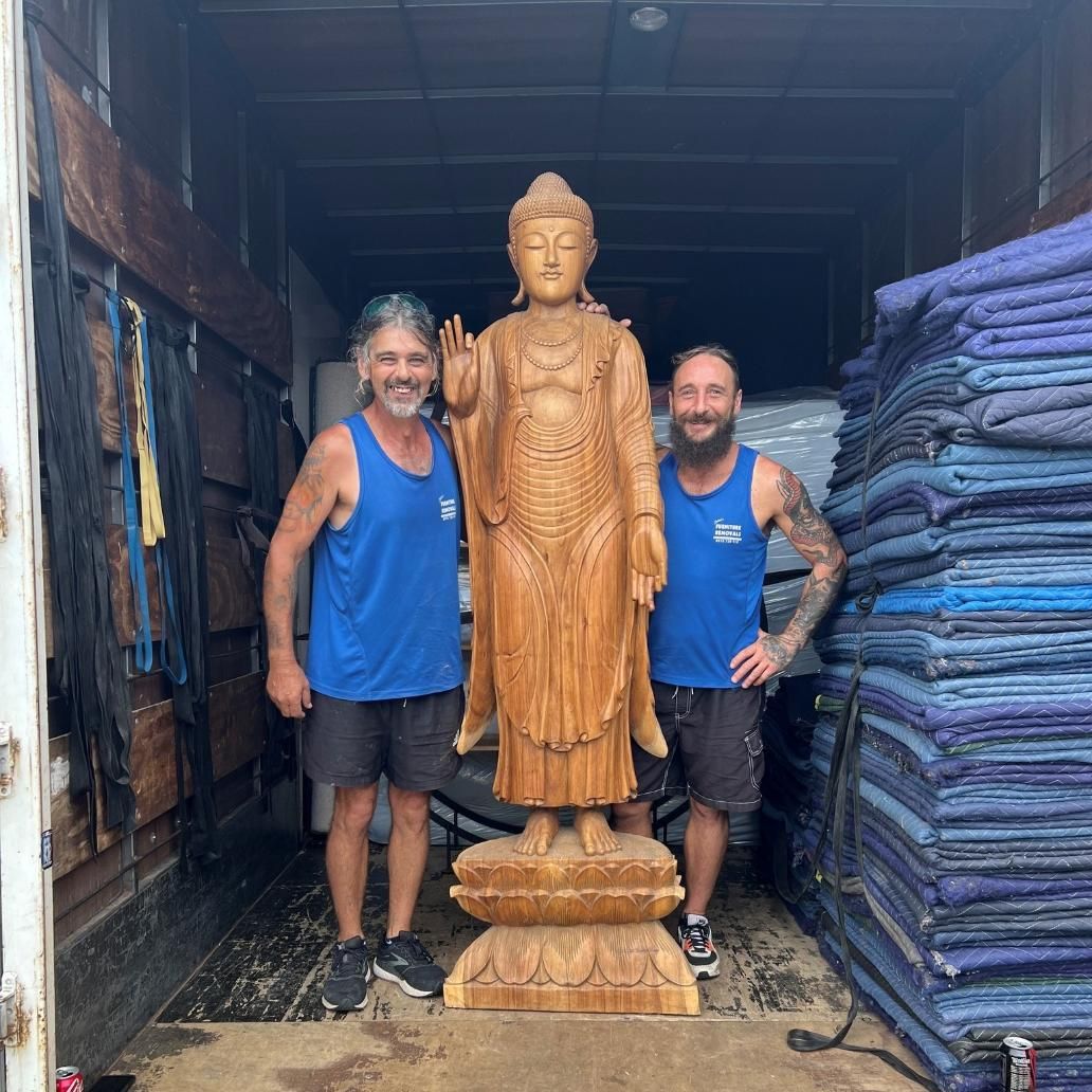 Two Men in a Truck Beside a Tall Wooden Buddha Statue — John's Furniture Removals in Maroochydore, QLD