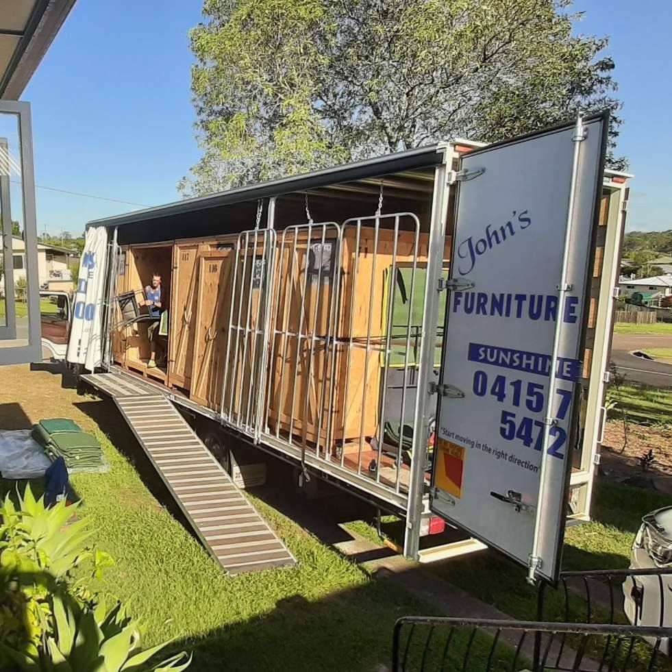 Truck Loaded With Wooden Doors, Parked on a Grassy Lawn — John's Furniture Removals in Mountain Creek, QLD