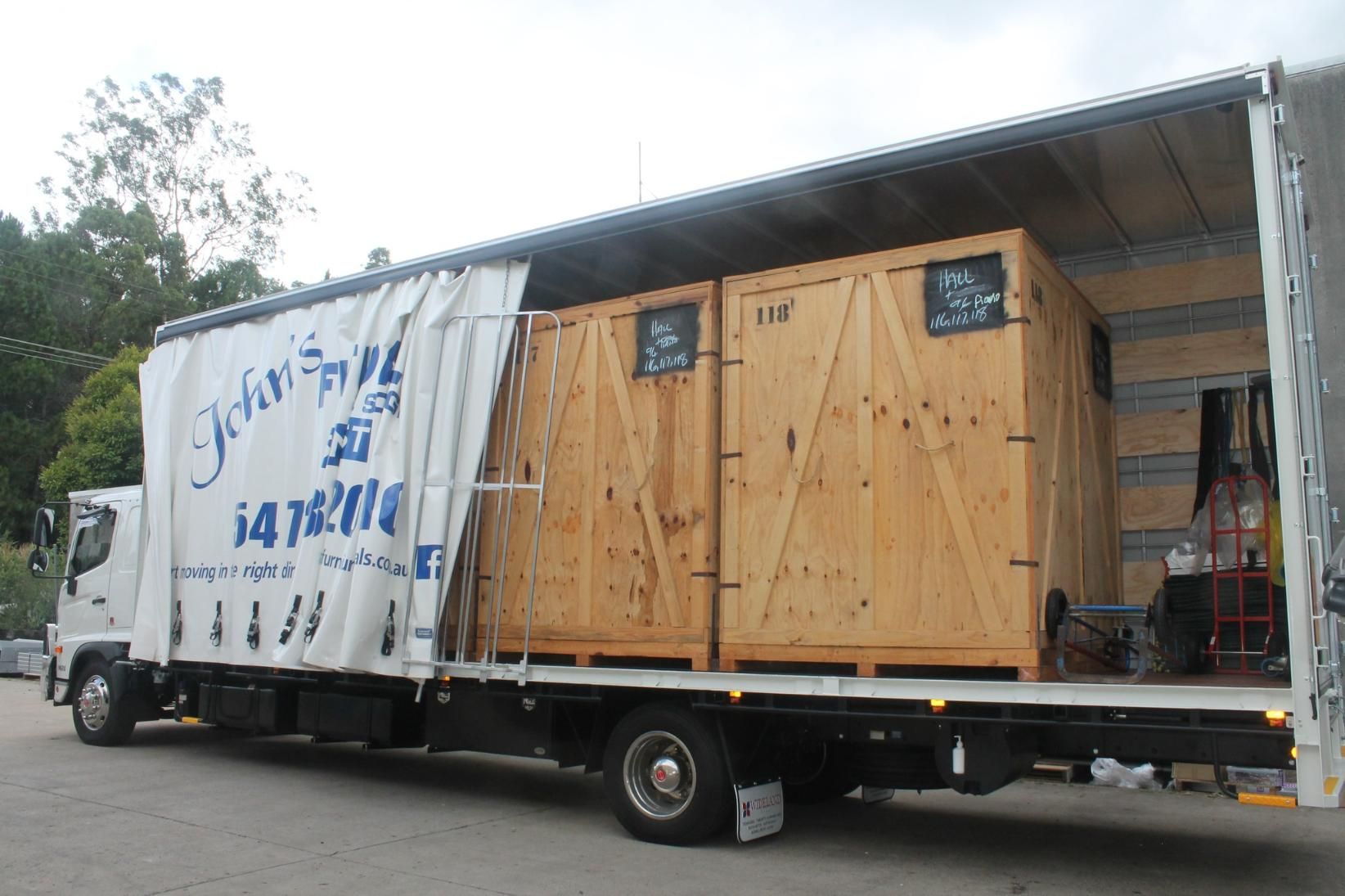 A Moving Truck Loaded With Two Large Wooden Crates, Parked Outdoors — John's Furniture Removals in Beerwah, QLD