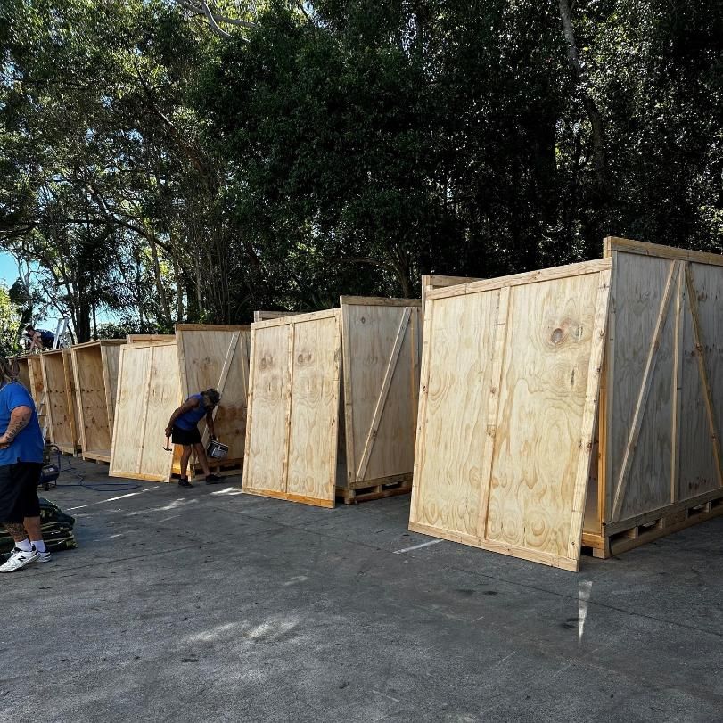 Wooden Crates on Pallets Outside, People in the Background — John's Furniture Removals in Nambour, QLD