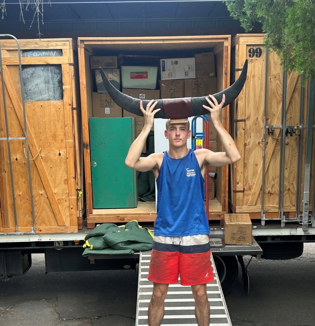 A Man Holding Large Bull Horns in Front of a Moving Truck Filled With Boxes — John's Furniture Removals in Nambour, QLD