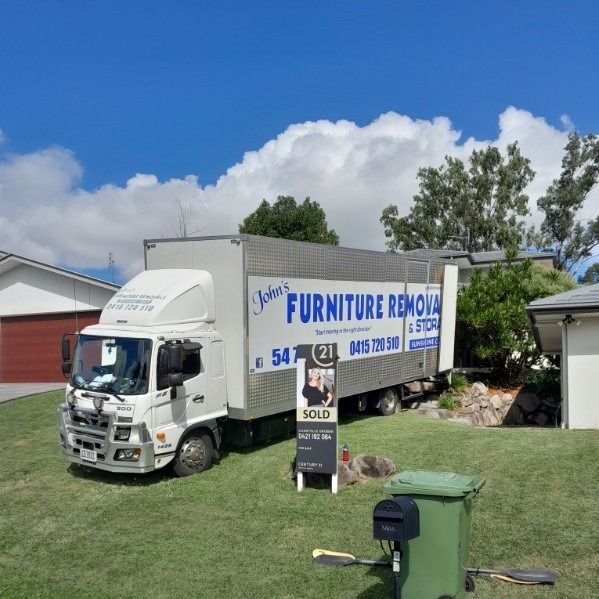 Moving Truck Parked on a Lawn Next to a Sold House — John's Furniture Removals in Gympie, QLD
