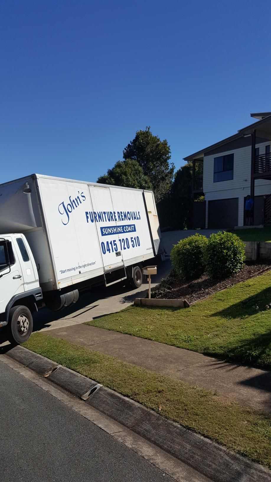 A White Moving Truck Parked On Driveway Outside House— John's Furniture Removals in Mountain Creek, QLD