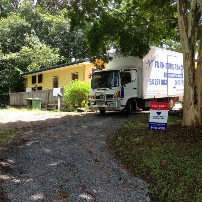 Removalist Truck Outside House For Sale — John's Furniture Removals in Noosa Heads, QLD