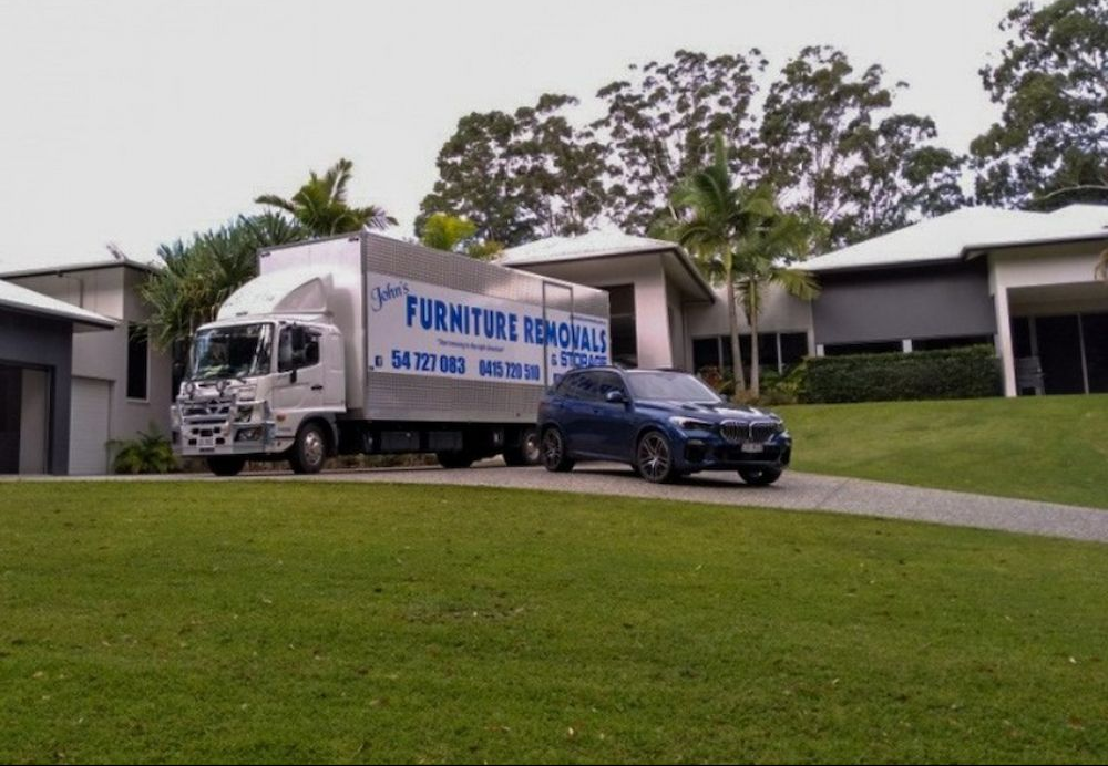 Removalist Truck and Car Parked Out Of Front Of House — John's Furniture Removals in Yandina, QLD