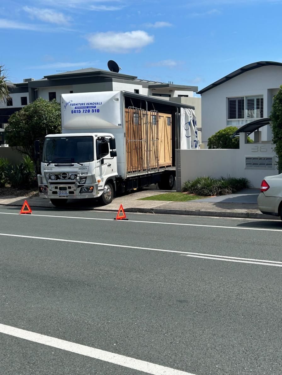 Moving Truck Parked in Front of Houses; Orange Cones on Road — John's Furniture Removals in Sunshine Coast, QLD