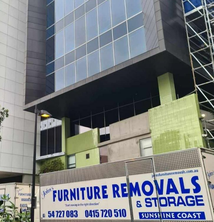 Moving Truck Parked in Front of a Tall Office Building— John's Furniture Removals in Caloundra, QLD
